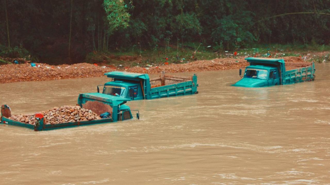Three green trucks in a flooded area