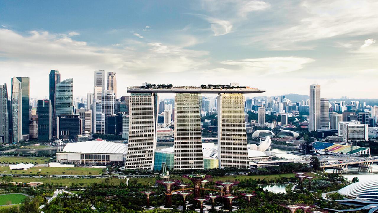 A tall, three-pillared, building in a city landscape.