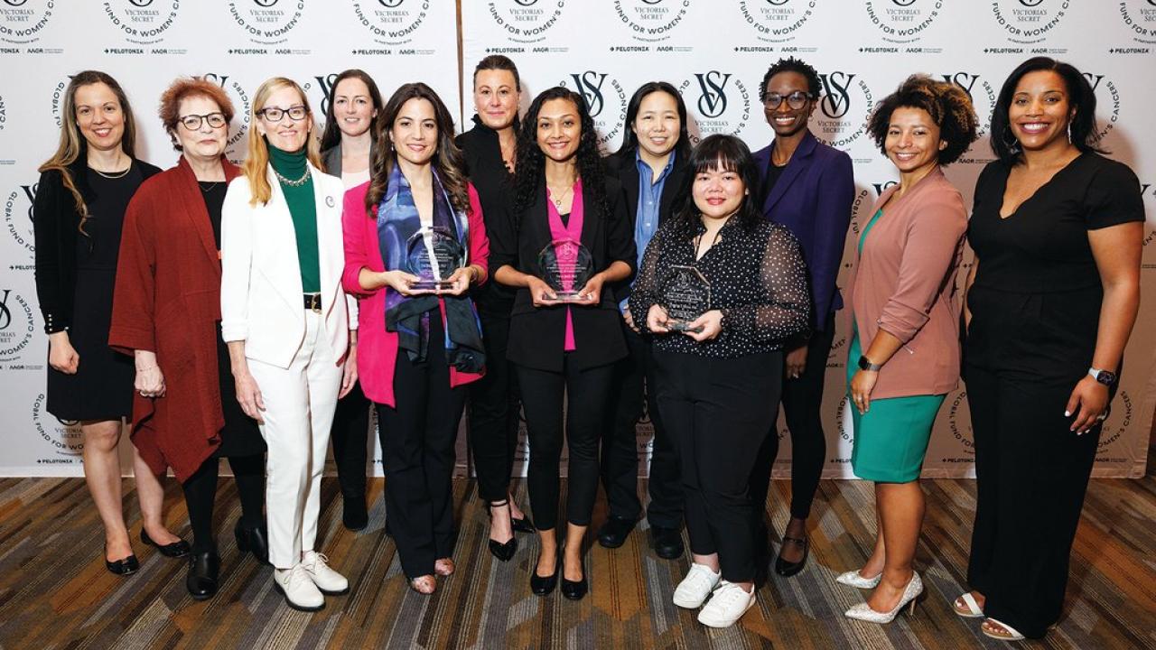 A group of women, 3 holding glass awards, in front of a VS Global Fund for Women's Cancer backdrop