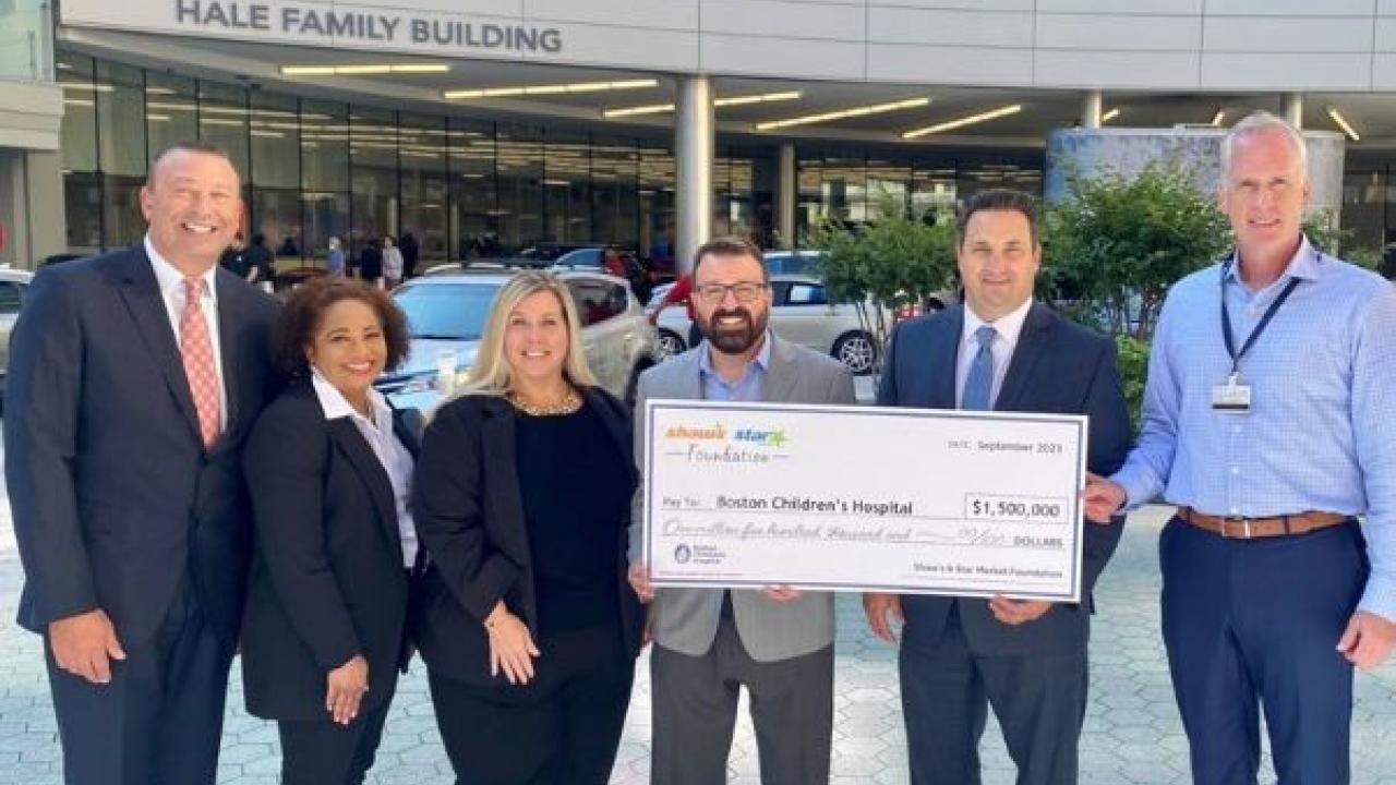 Group of people holding large check in front of Boston Children's Hospital