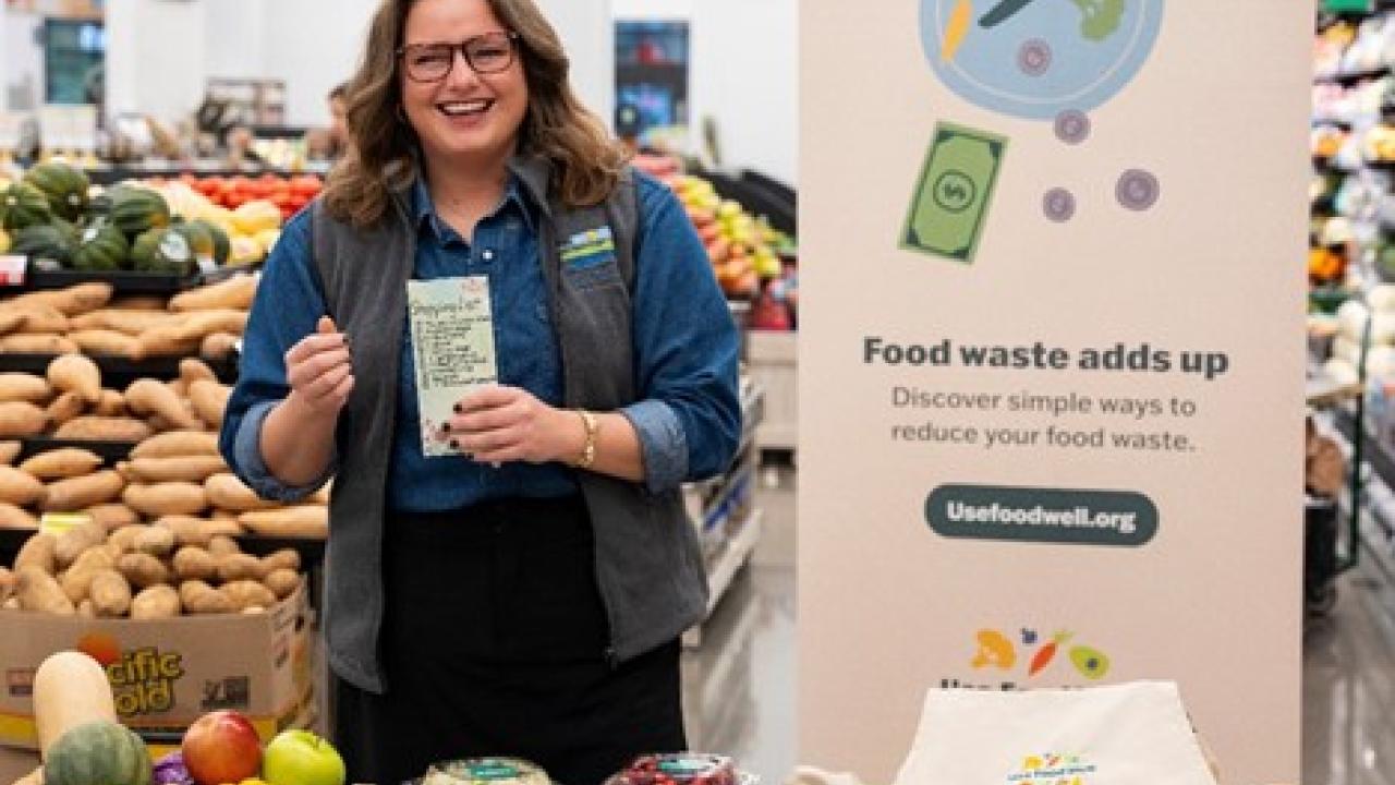 Person at grocery store with stand about food waste prevention