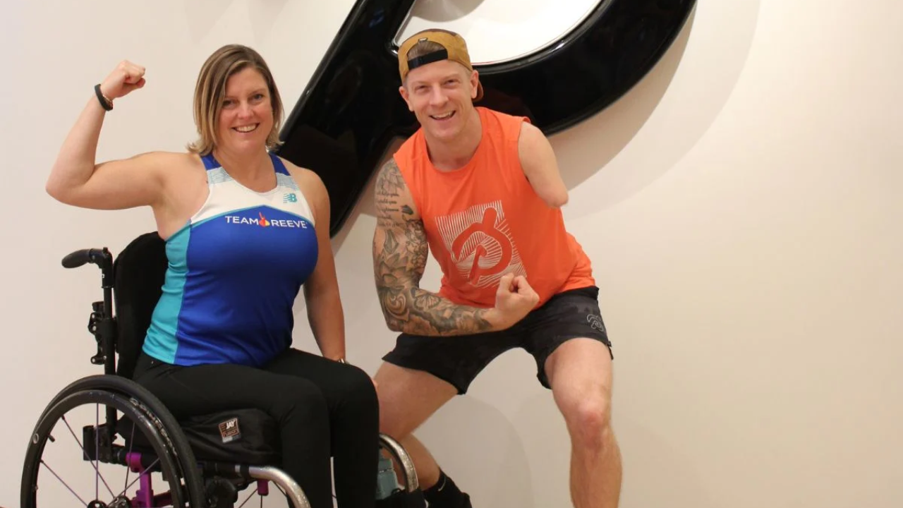 2 people flexing in front of the Peloton logo