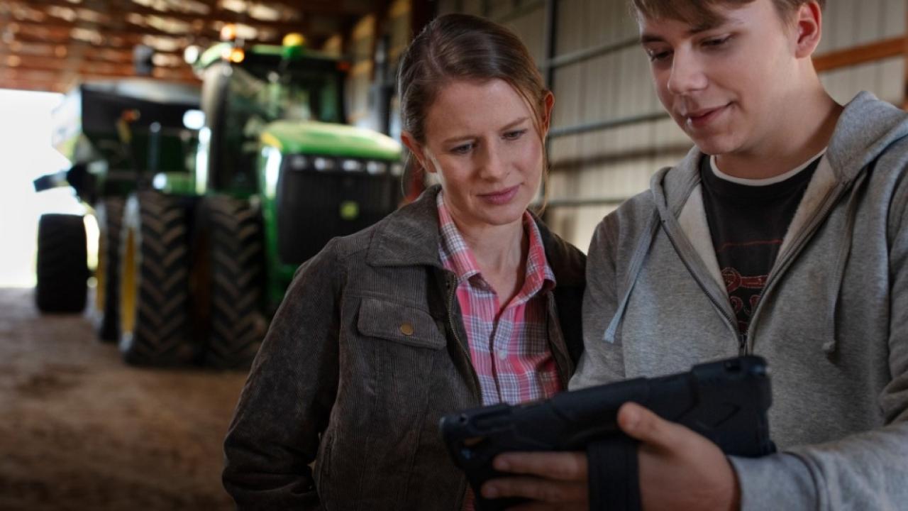 two people looking at a computer screen in a barn