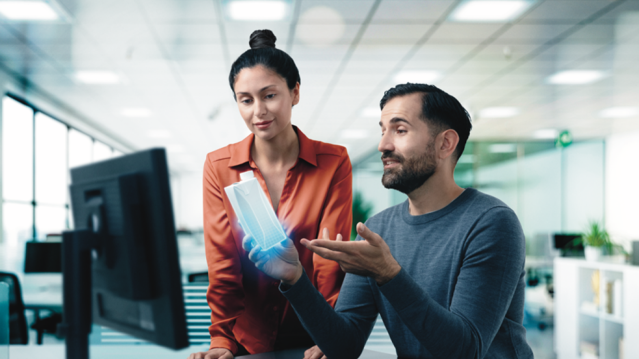 Man and woman holding carton in front of computer