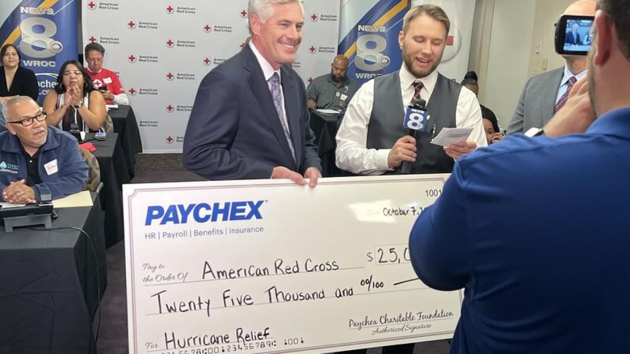 Man holding big check of donation from Paychex