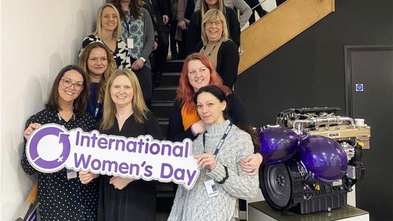 Women on staircase holding International Women's Day sign