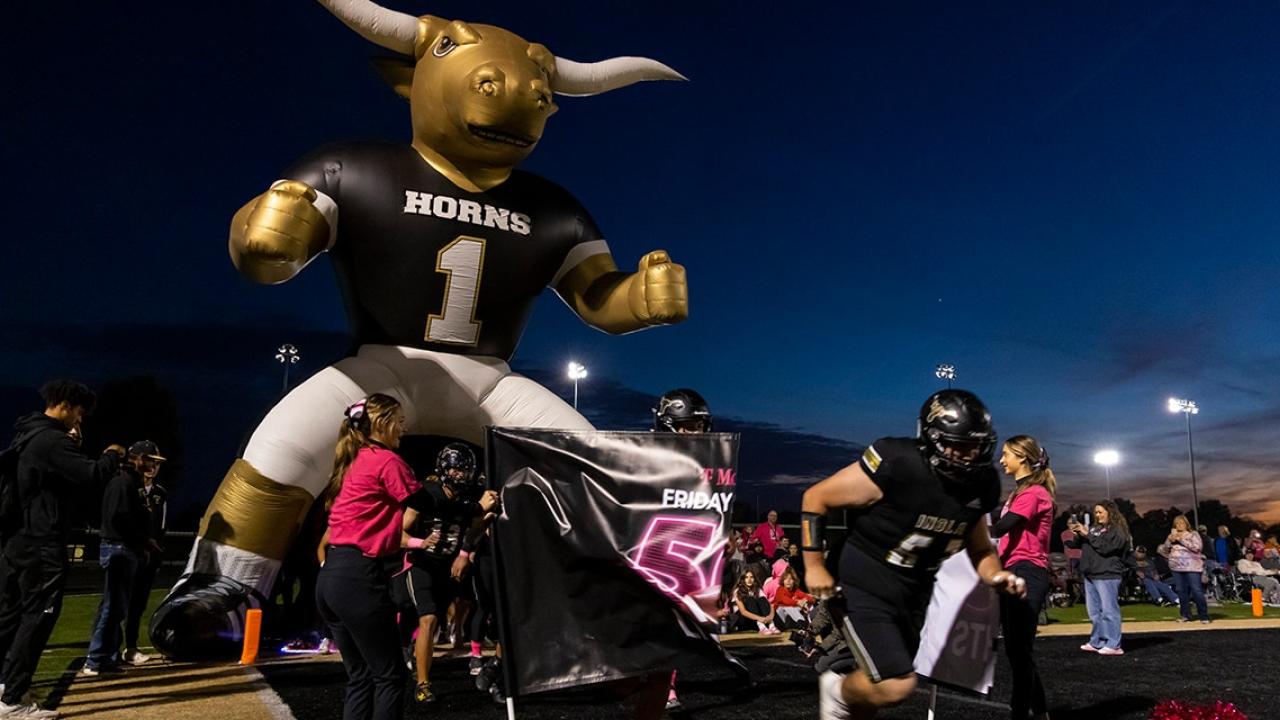Football players run through banner