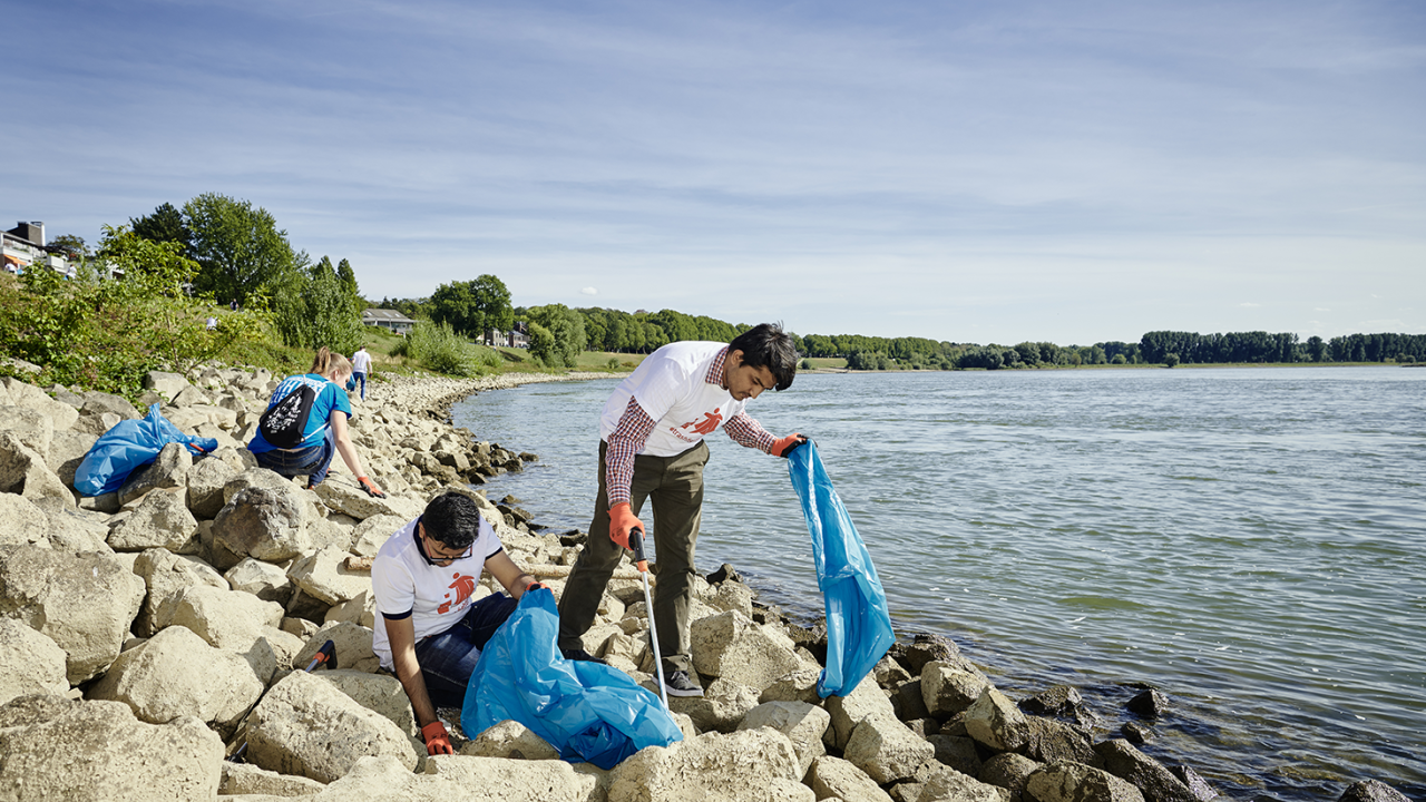 People picking up garbage by a body of water