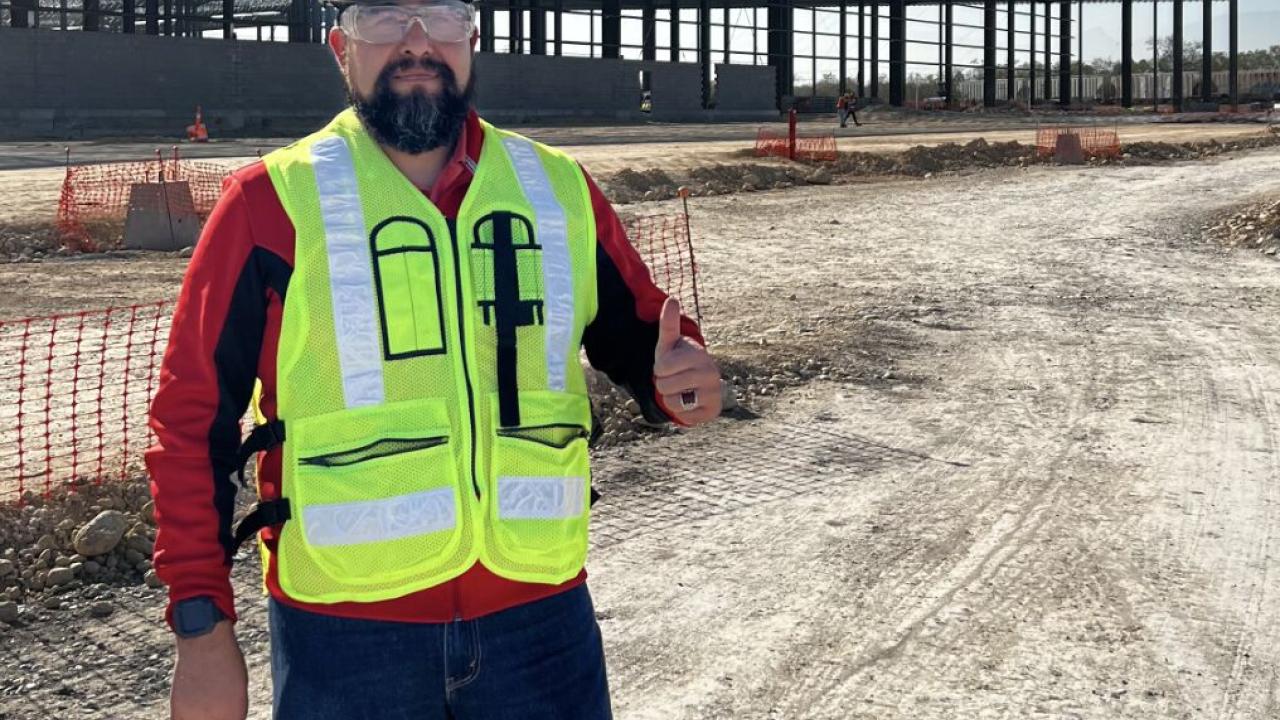 Person standing outside in hard hat and reflective vest