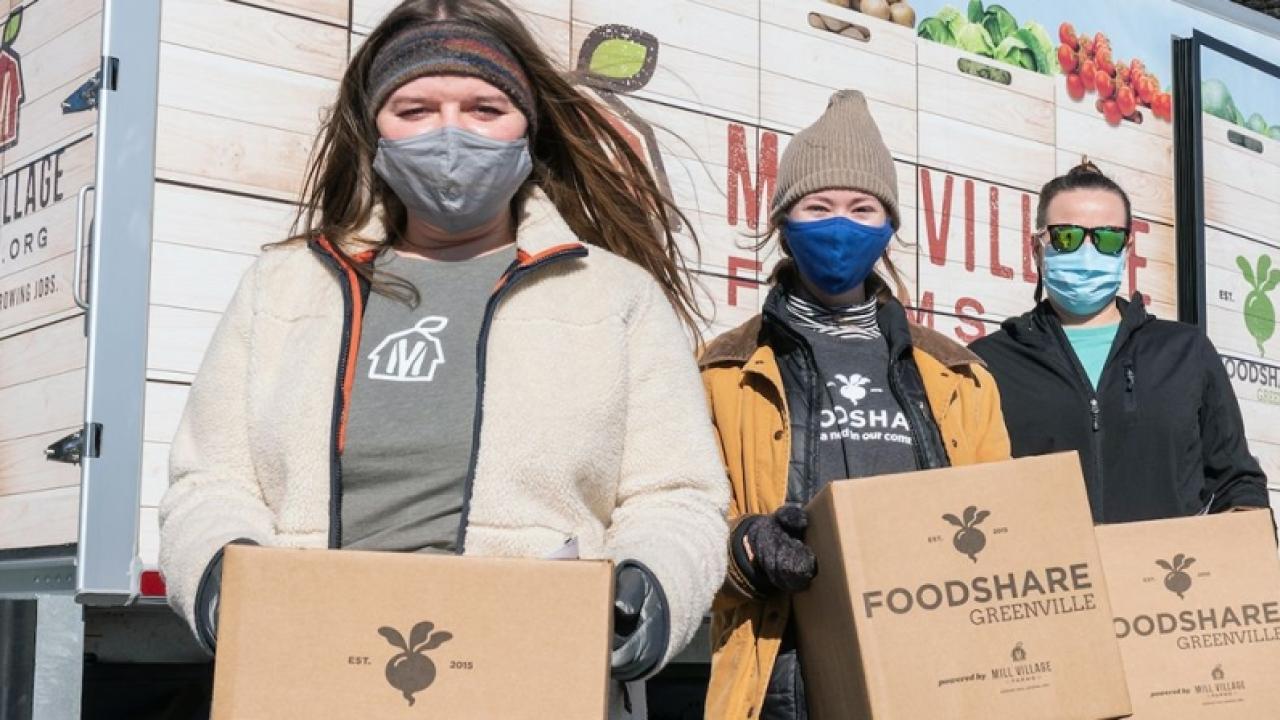 4 masked volunteers carrying boxes