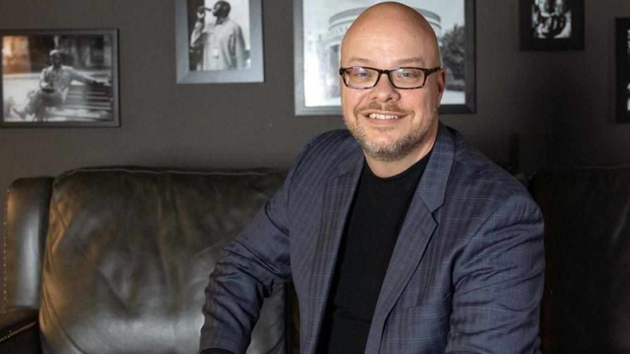 Andy Smith in a gray suit, sitting on a dark sofa