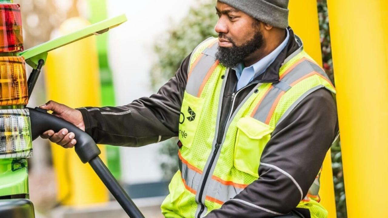 worker in a safety vest plugging in an electric bus