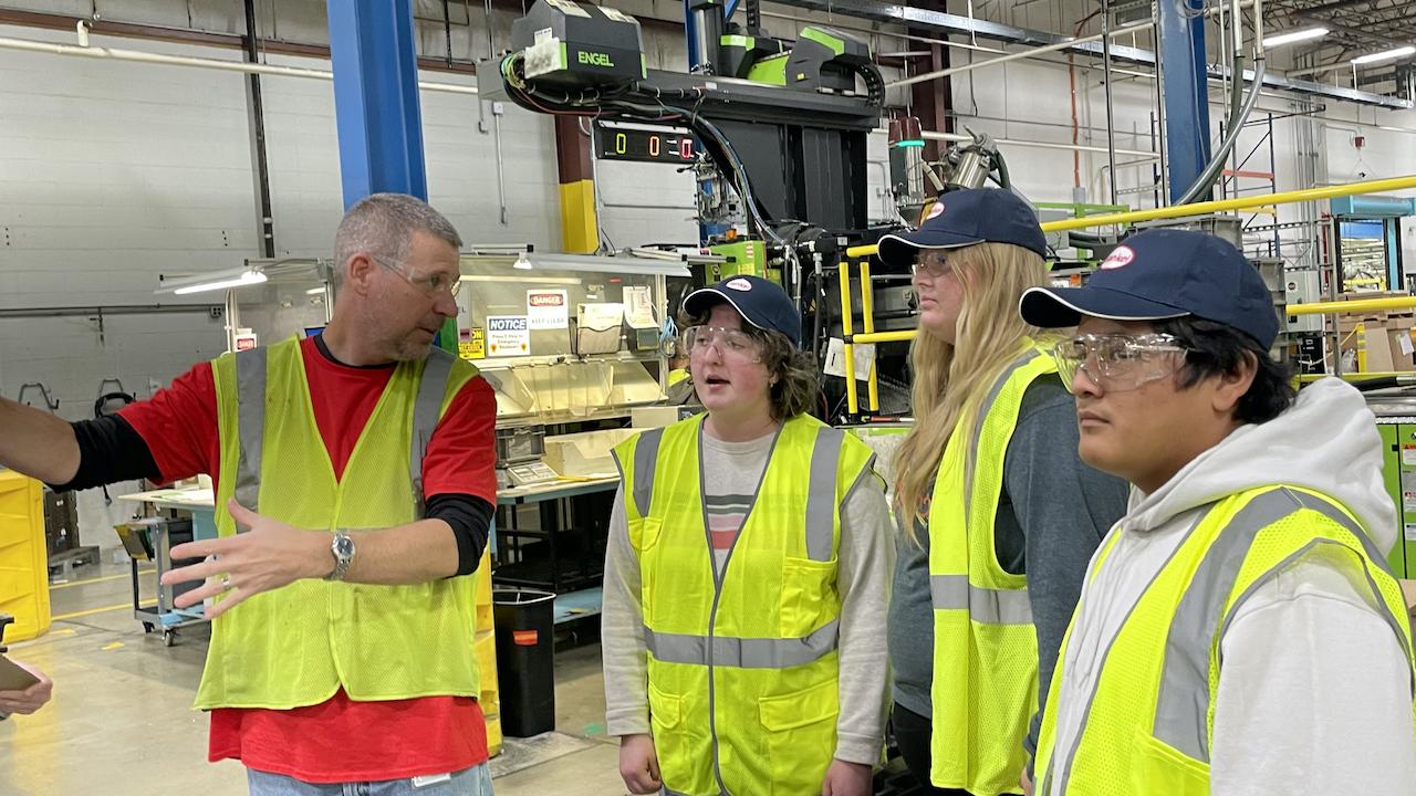 Group of people in hi-visibility vests in a factory