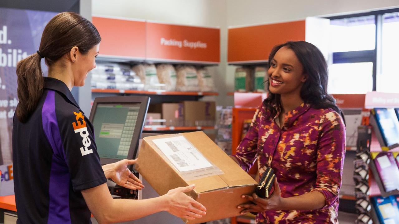 FedEx employee hands box to smiling customer