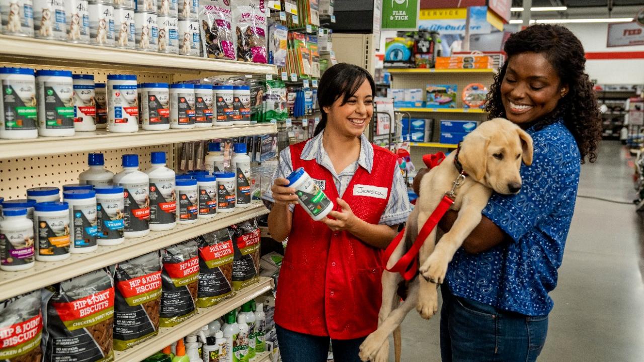 Tractor Supply employee helping a customer who is holding her dog