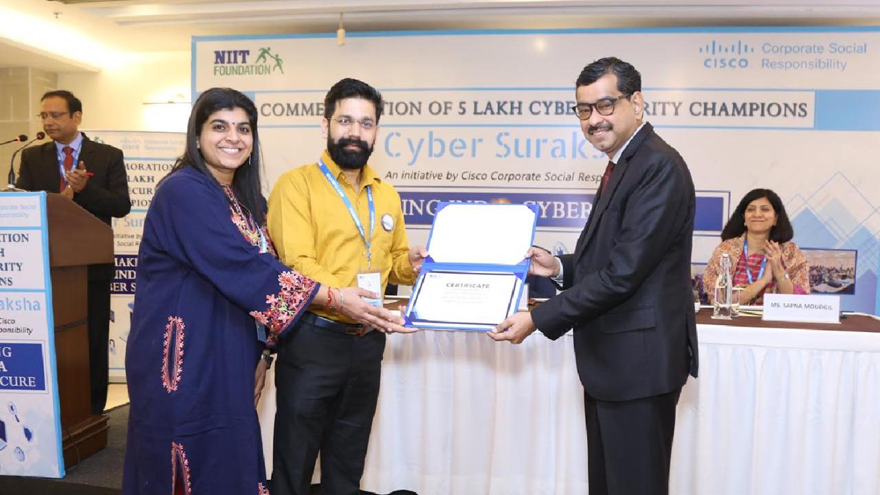 Three smiling people holding an award certificate. Others behind them.