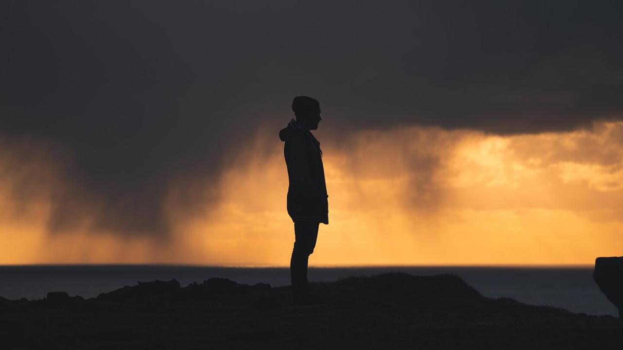 A silhouette of a person stood on a hill