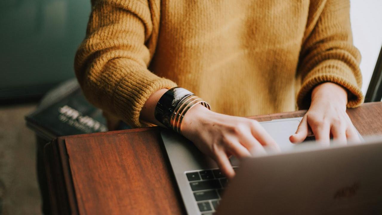 Person seated at a desk typing on a laptop.