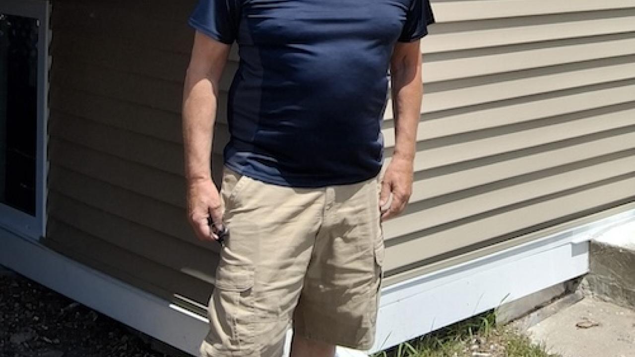 Mark shown in front of his home.
