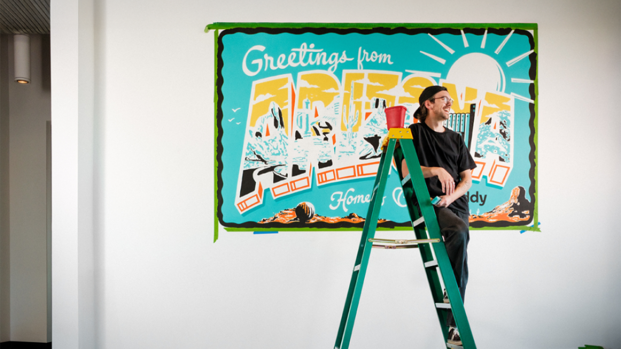 person smiling while standing on a short ladder