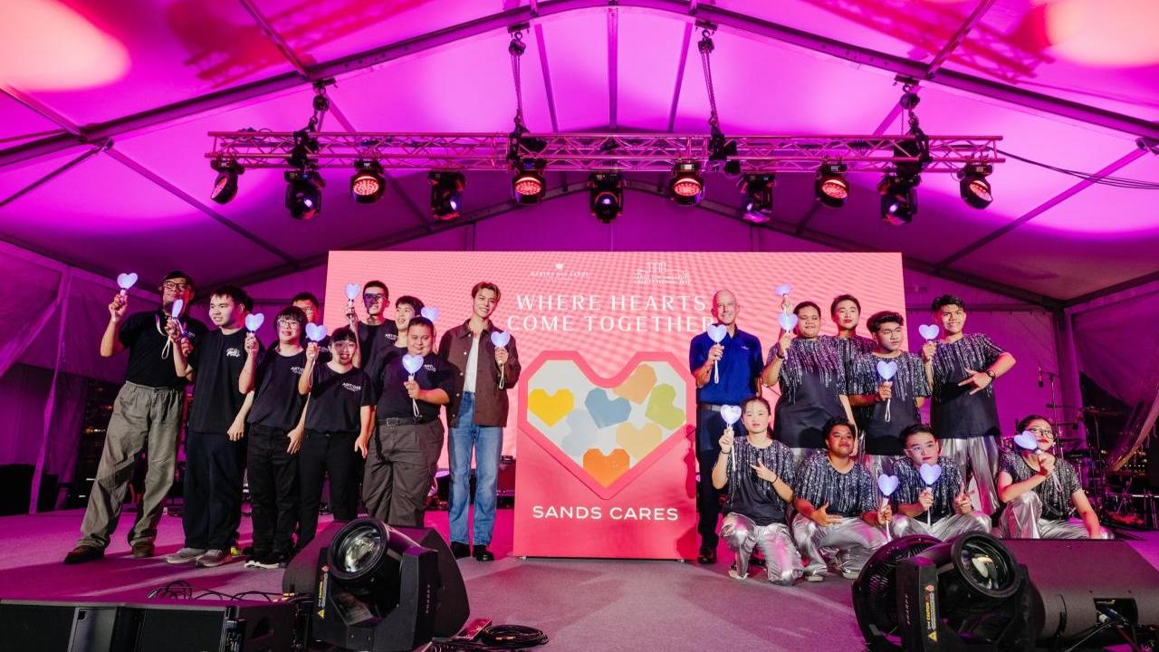 People posing on a stage, holding up a heart