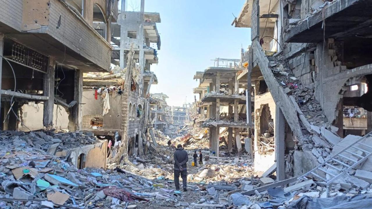 Man walks through street lined with destroyed buildings