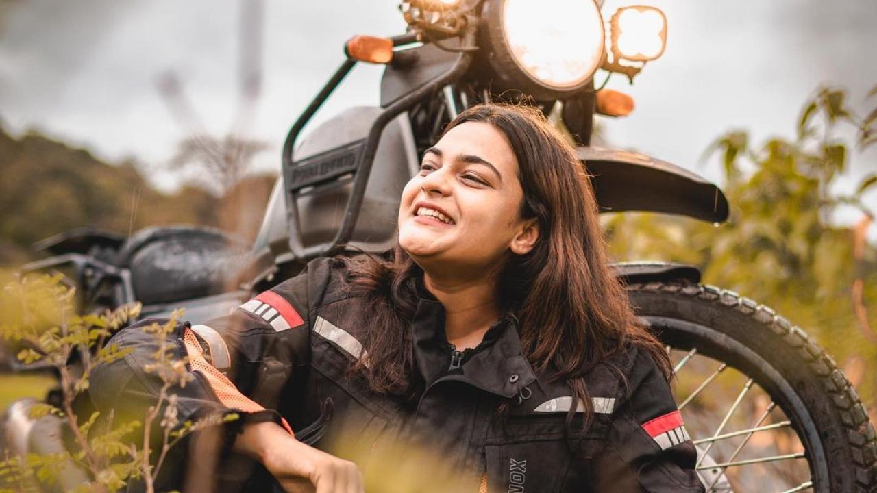 Vishakha Fulsunge in a field, sitting in front of her motorcycle