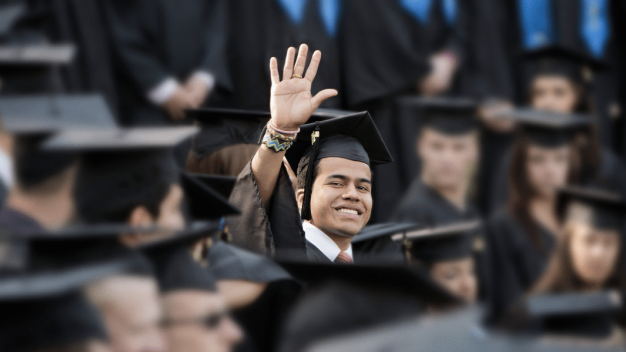 man wearing cap and gown waving