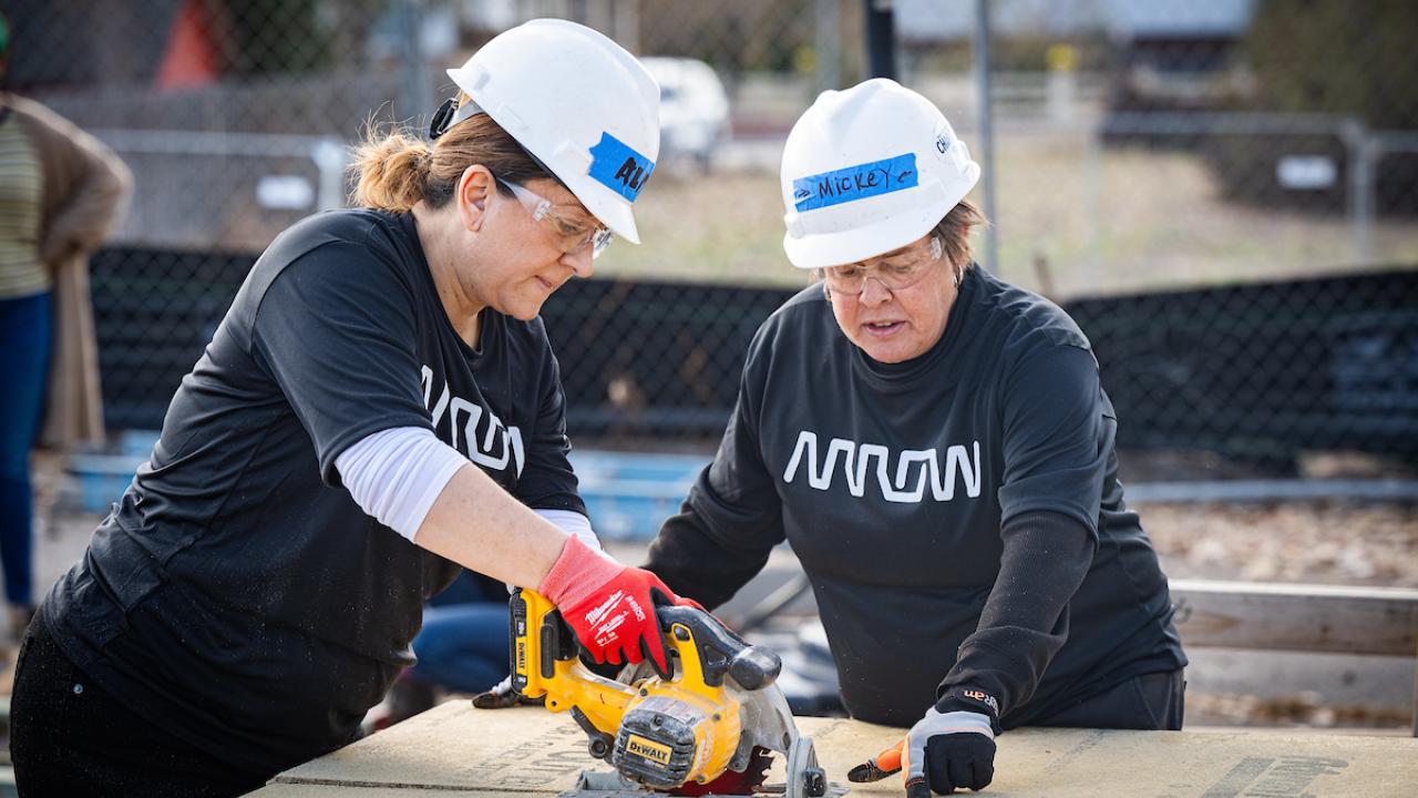2 arrow employees using a saw
