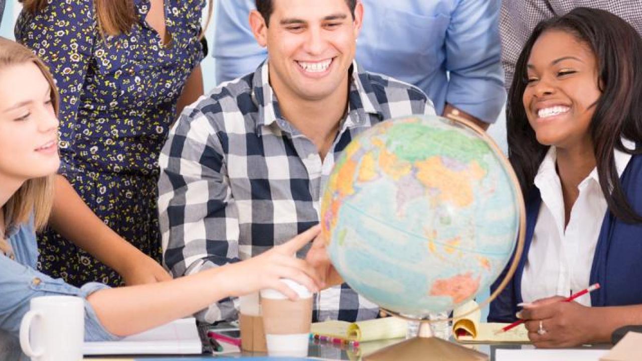 3 people having a discussion around a globe