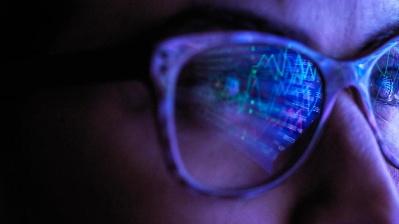 Person wearing glasses reflecting numbers and graphs