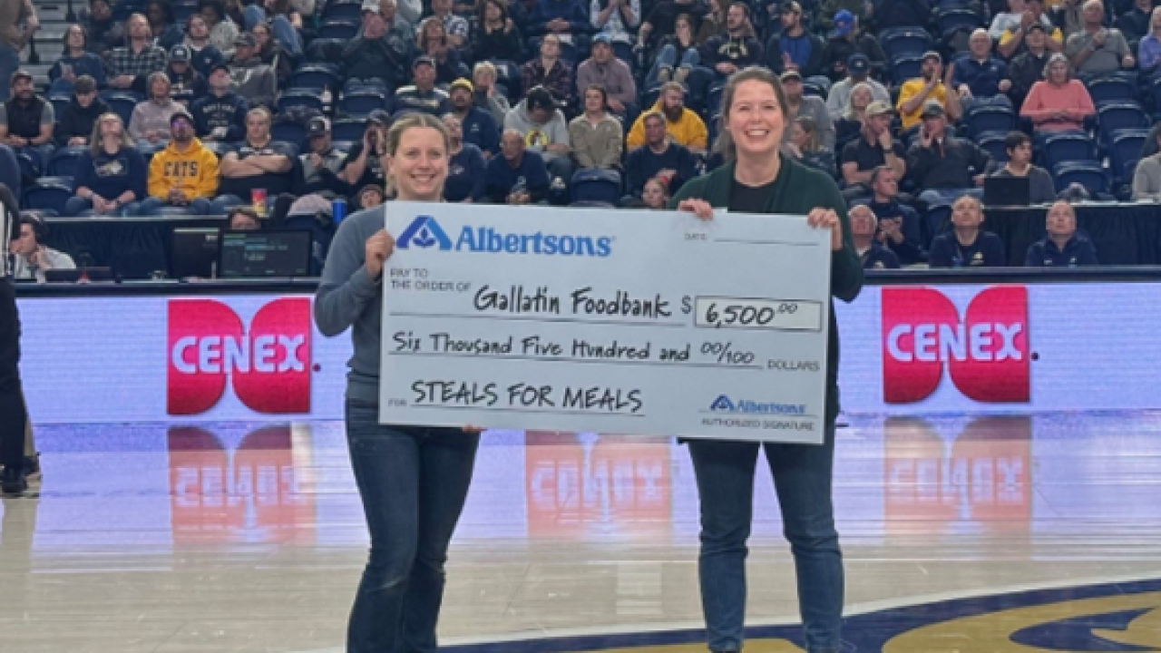 Two people holding a check on a basketball court
