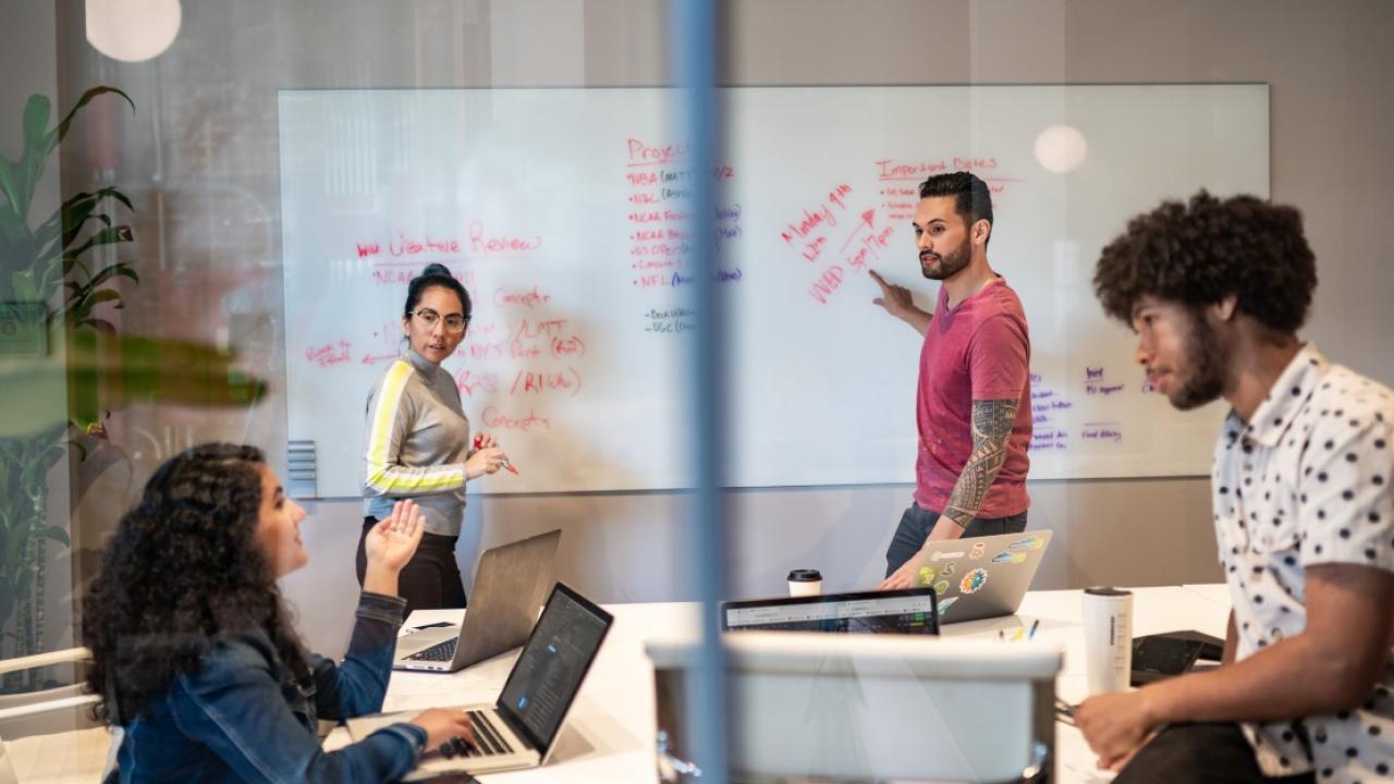 people working together and writing notes on a whiteboard