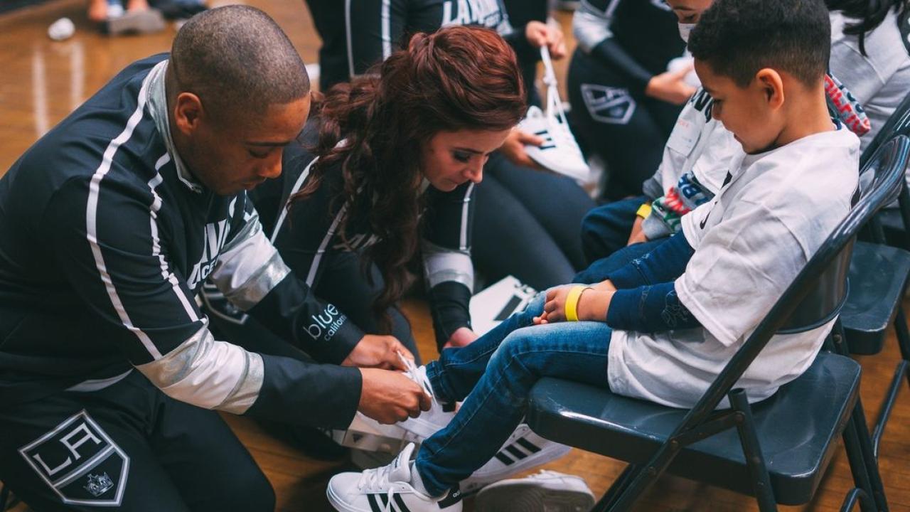 LA Kings Hockey Development Team and LA Kings Ice Crew help students put on their new shoes.