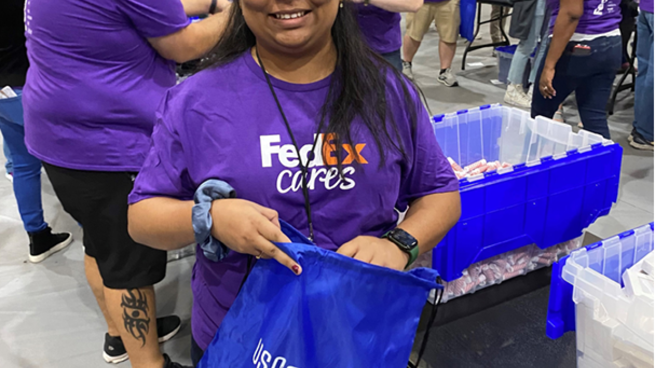 Volunteers in groups packing blue bags. One smiling at the camera.