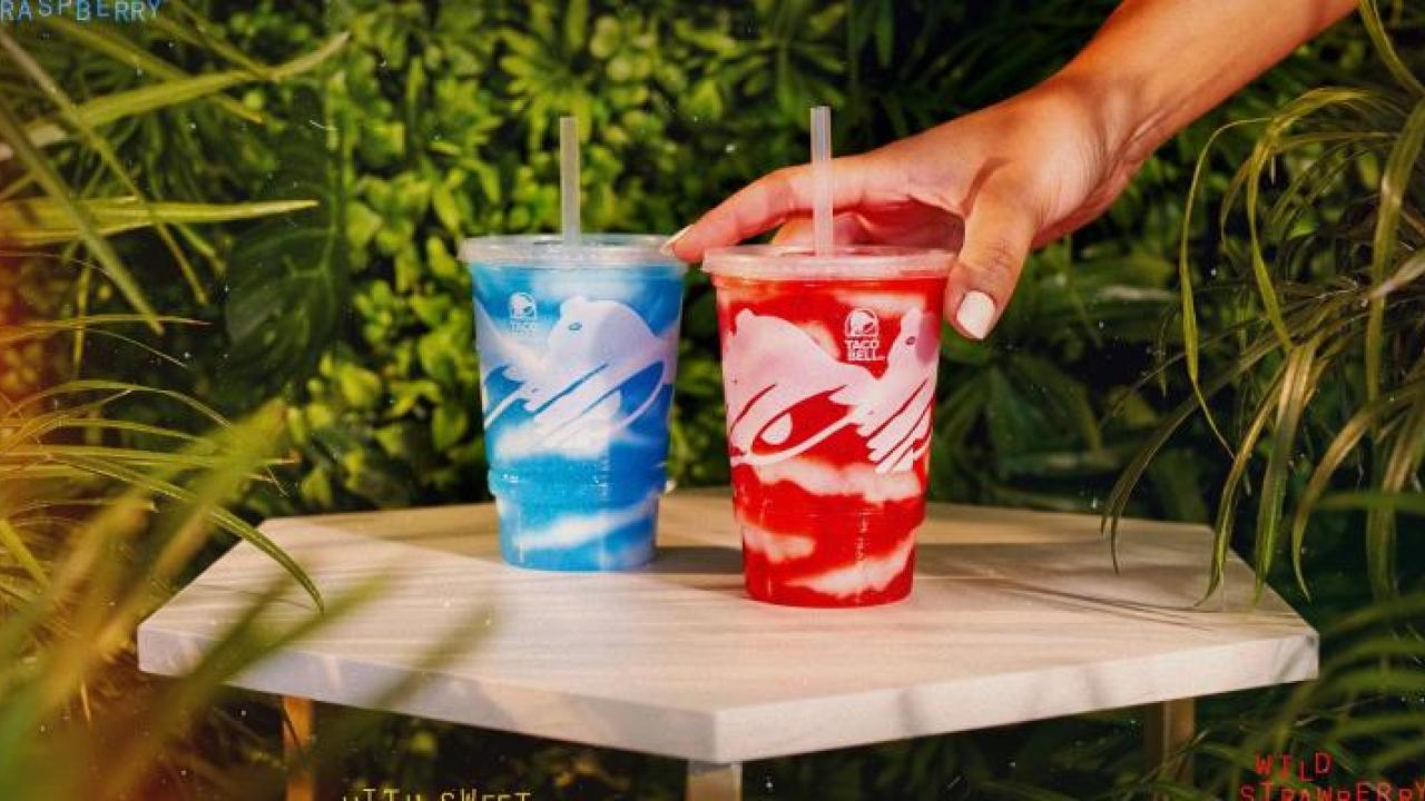 One blue and one red island berry freeze, with a hand reaching for the red one.