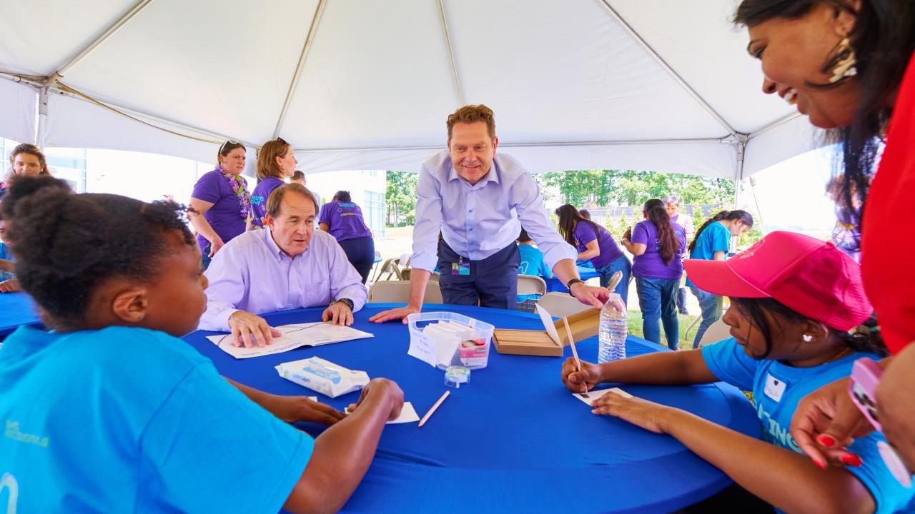 CEO stands over table teaching students