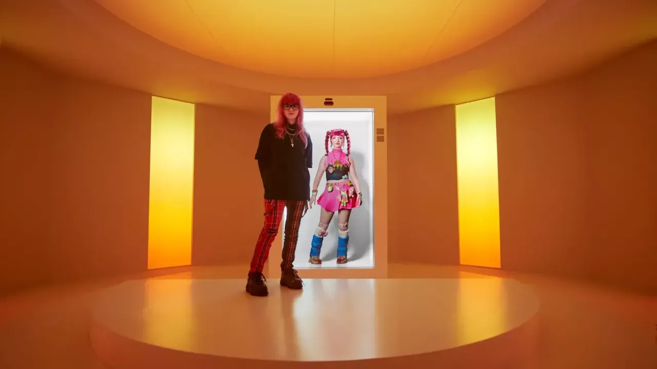 A person stood in front of a screen displaying an AI avatar 