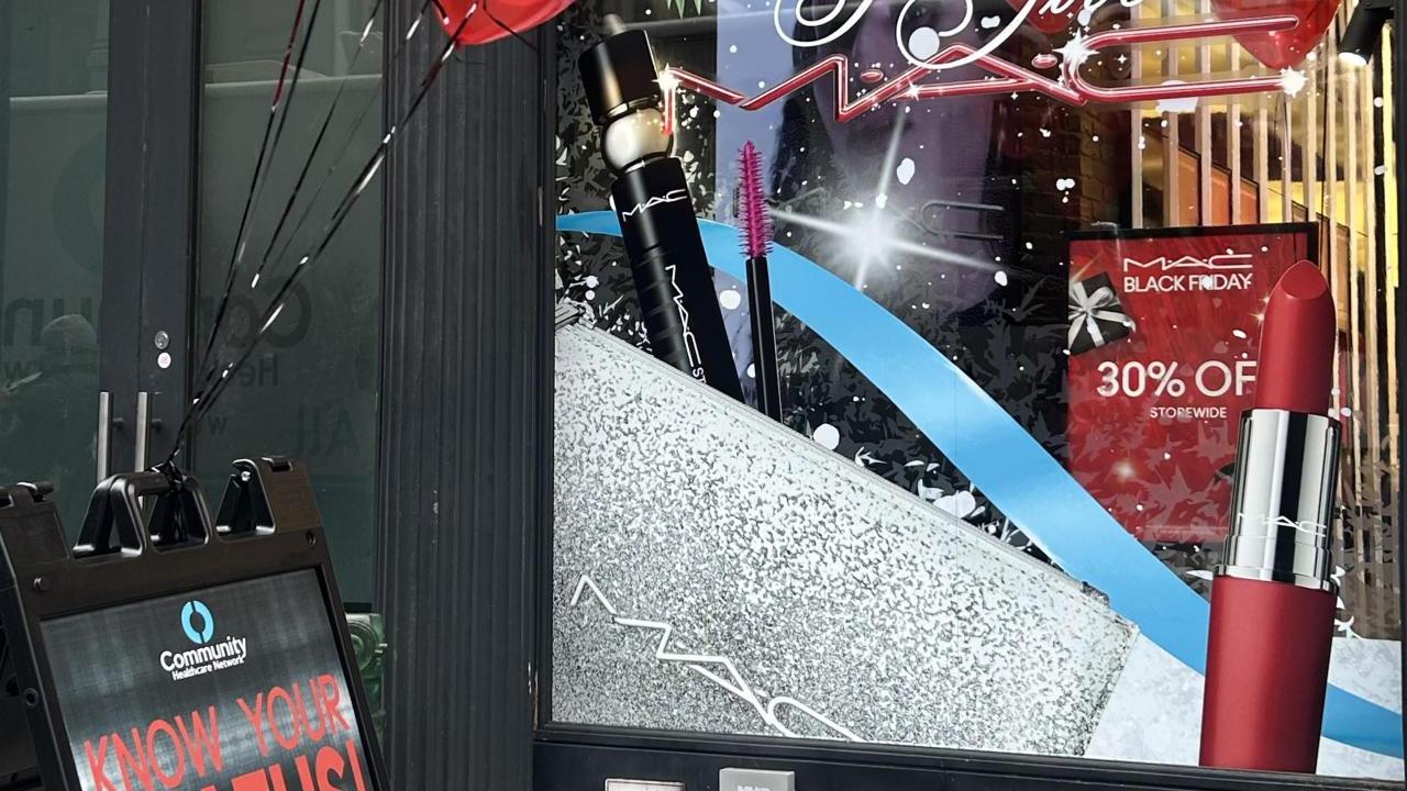 MAC store front with a "Know your status" board with red balloons in front.