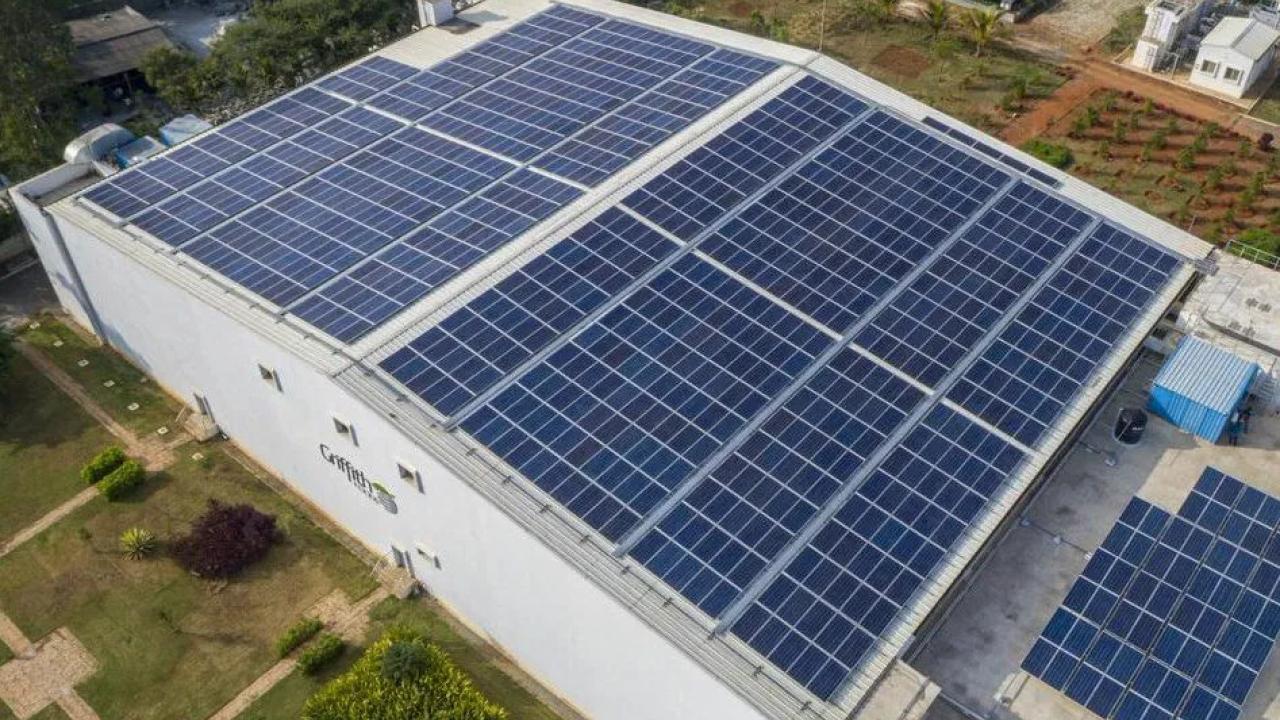 Aerial view of a large building, the roof covered with solar panels.
