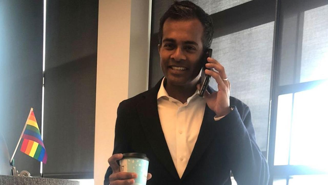Abiman Rajadurai talking on a cell phone, smiling