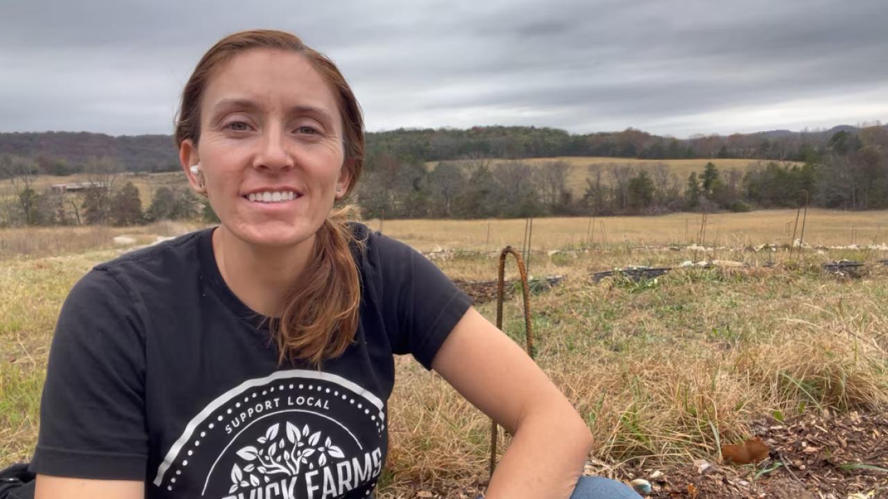 A young person shown in a field on a farm.