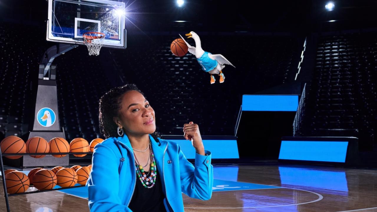 Dawn Staley and the Aflac Duck shown slam dunking a basketball.
