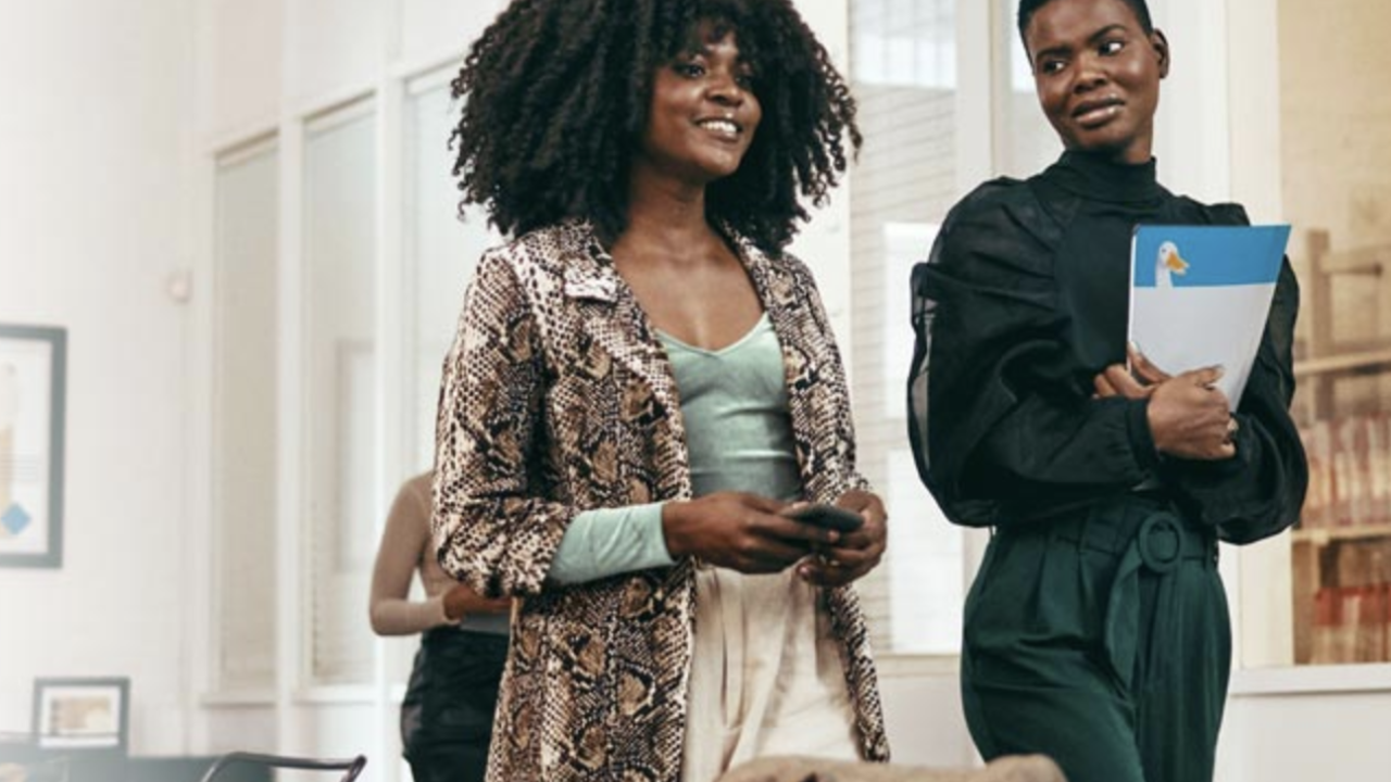 Two women of color walking through an office.