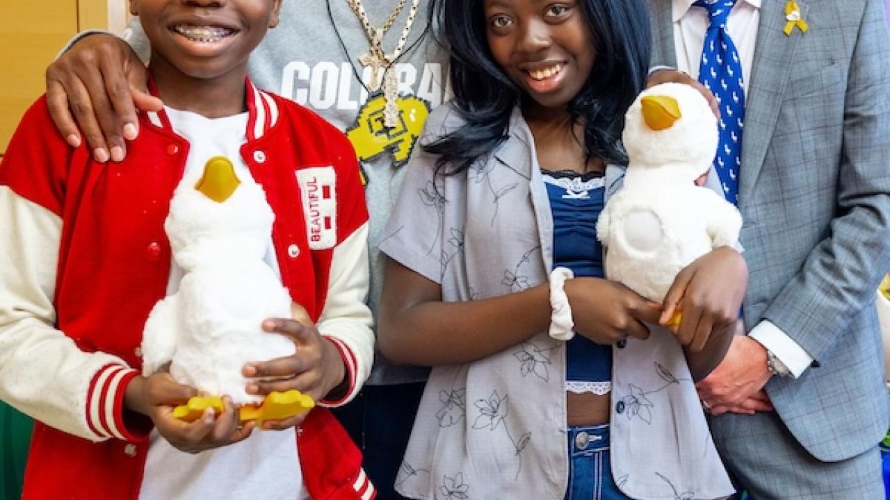 Deion Sanders shown with young patients holding the Aflac Duck.