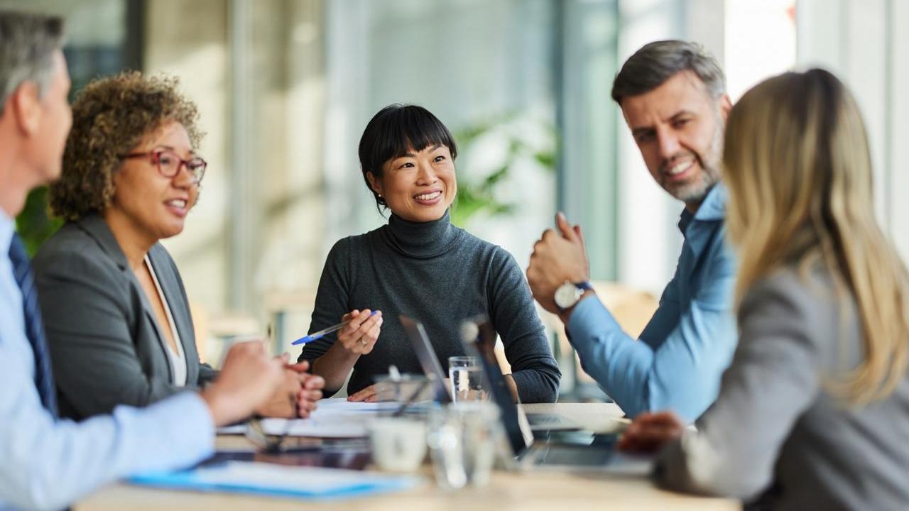 Team of five coworkers sitting around a table and smiling