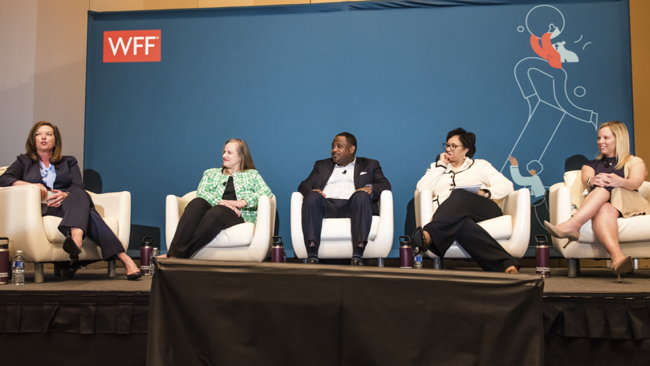 5 people sit on stage with WFF backdrop behind them