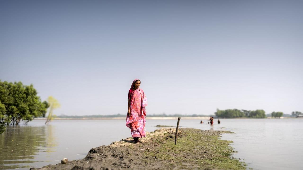 A woman walks along a flooded field. 