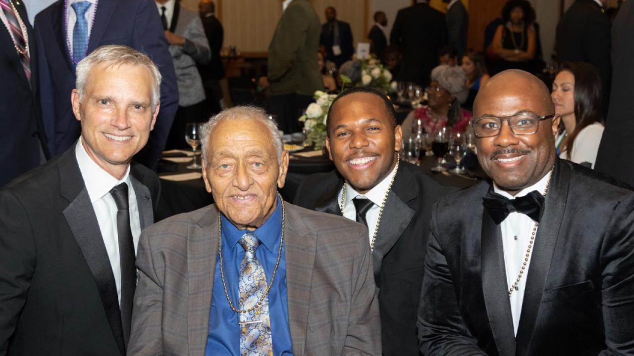 four people in suits and ties at a fancy banquet
