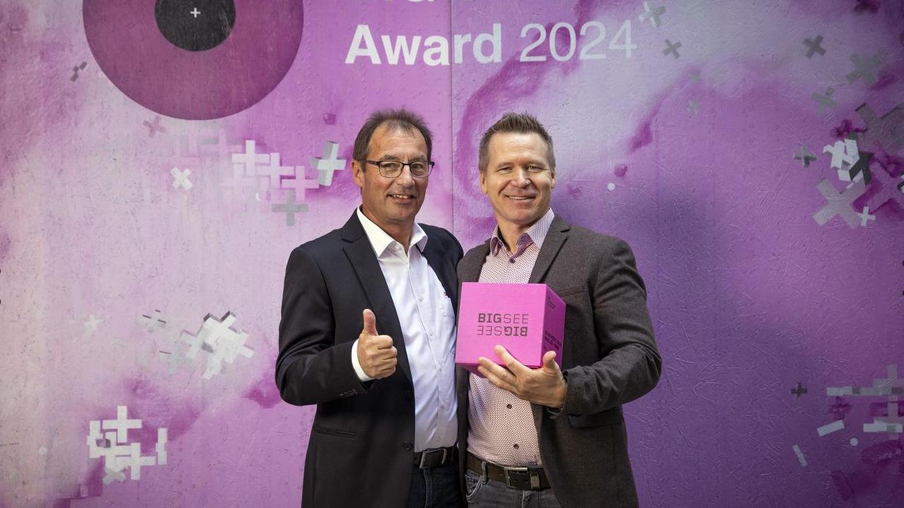 Two people stood together holding an award 